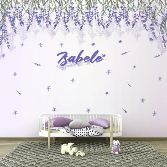 Papel de parede floral lilás 'Isabele' decorando um quarto infantil com berço branco, almofadas lilás e brinquedos