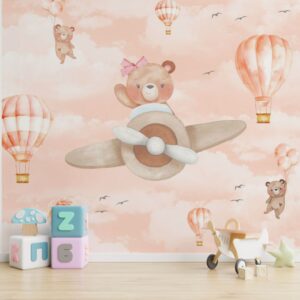 Papel de parede infantil com ursinho aviador voando entre balões de ar quente e céu rosa.