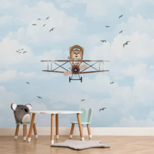 Papel de parede infantil com ursinho aviador voando em um céu azul com nuvens e pássaros